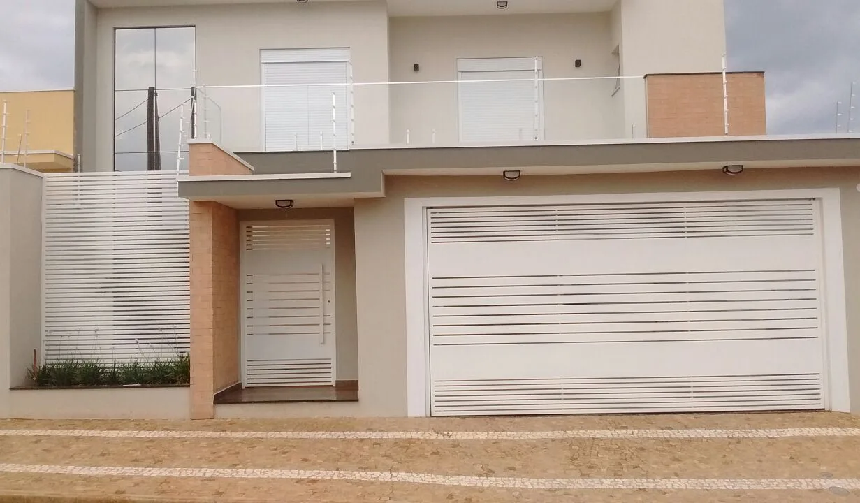 Fachada residencial com portão e porta social em metal branco